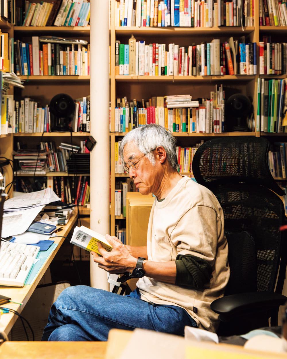 高橋源一郎が書斎で本を読んでいるところ